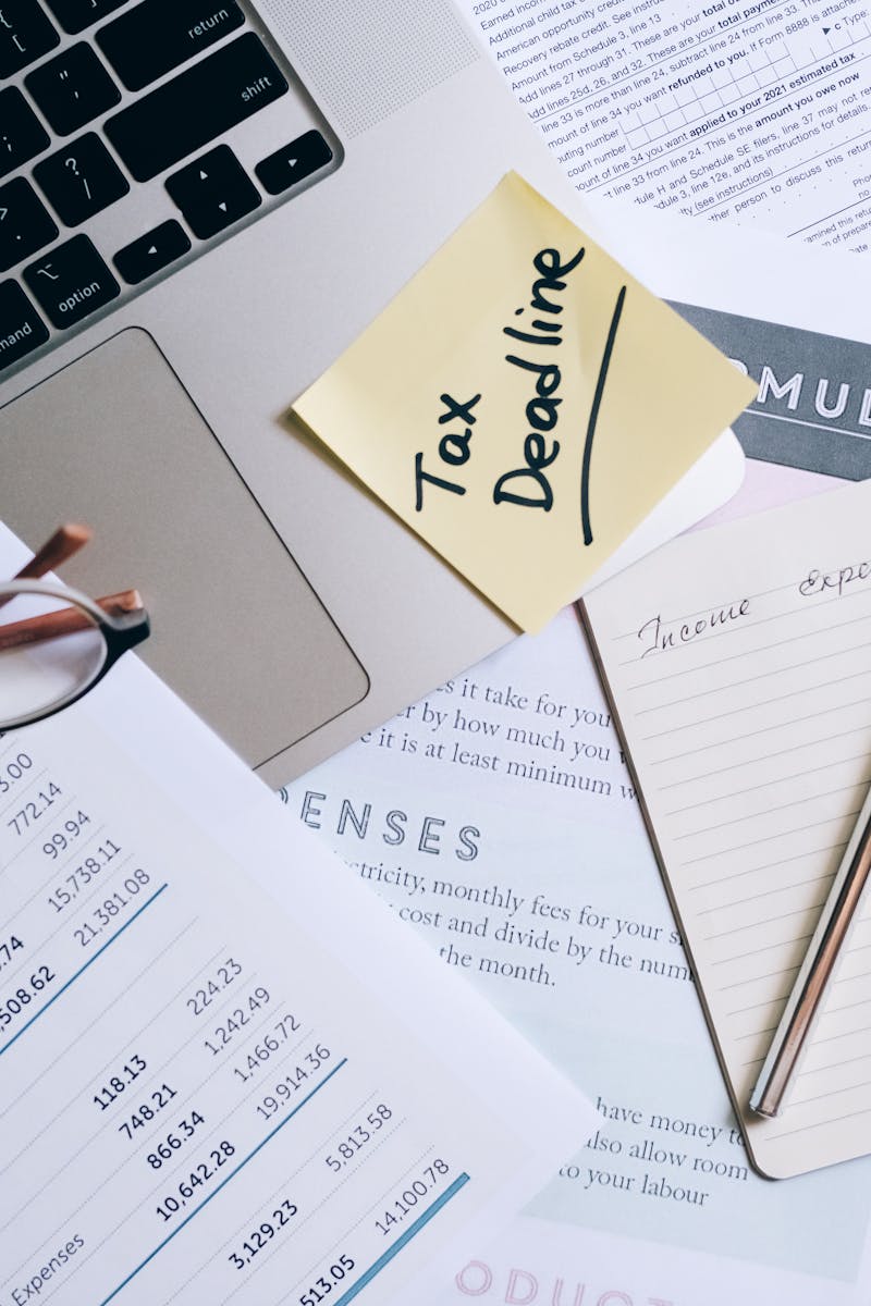 Workspace with laptop, documents, and tax deadline note for financial management.